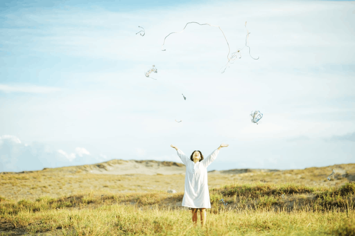 草原と白いワンピースの女性